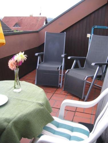 a balcony with a table and chairs and a vase of flowers at Haus-Voelker in Bermatingen