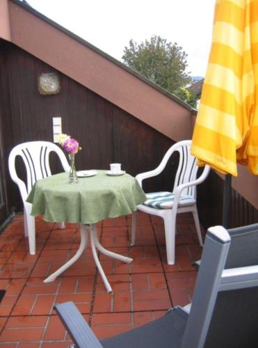 a table and chairs on a patio with a vase of flowers at Haus-Voelker in Bermatingen