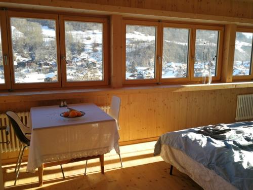 a room with a table and a bed and windows at B&B Gafaller in Jenaz