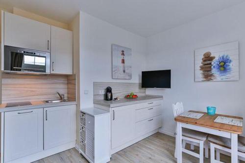 eine Küche mit weißen Schränken, einem Tisch und einem Esszimmer in der Unterkunft App. 8 in strandnaher Lage - Bäderstil-Villa in Wenningstedt/Sylt in Wenningstedt-Braderup
