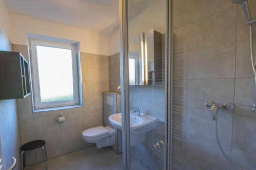 ein Bad mit einer Dusche, einem WC und einem Waschbecken in der Unterkunft Gemeinsamzeit-auf-2-Etagen-im-App-27-Strandhafer in Timmendorfer Strand