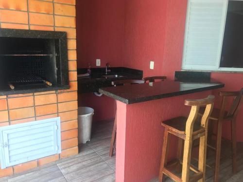 Una cocina con barra con dos taburetes y chimenea. en Sobrado 03 na Praia de Bombas, en Bombinhas
