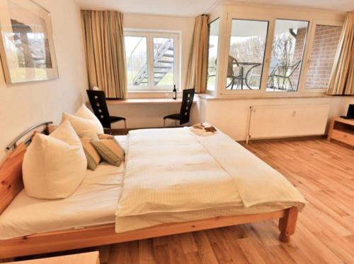 ein großes Bett in einem Zimmer mit zwei Fenstern in der Unterkunft Appartement 27a - Sandburg - mit Zugang zum Garten in Timmendorfer Strand