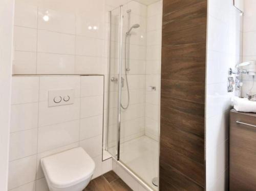 ein weißes Bad mit einer Dusche und einem WC in der Unterkunft Appartement 27a - Sandburg - mit Zugang zum Garten in Timmendorfer Strand