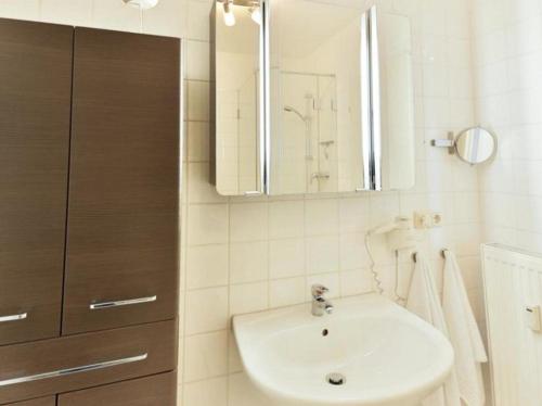 ein weißes Badezimmer mit einem Waschbecken und einem Spiegel in der Unterkunft Appartement 35 - Ostseehafen in Timmendorfer Strand