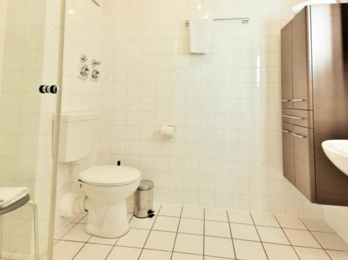 ein weißes Bad mit einem WC und einem Waschbecken in der Unterkunft Appartement 32 - Strandspaziergang in Timmendorfer Strand