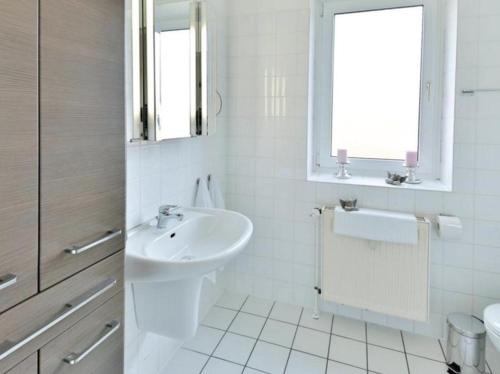 biała łazienka z umywalką i toaletą w obiekcie Appartement 33 - Ostseeluft w mieście Timmendorfer Strand