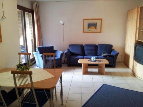 a living room with a blue couch and a table at 2-Zimmer-Appartement-im-Ostseehaus-Petersen in Grömitz