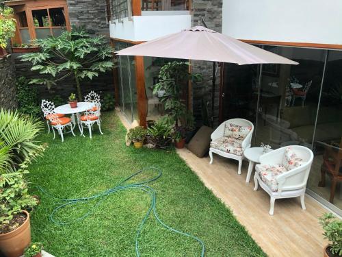 a patio with chairs and an umbrella and grass at Casa Campo Machu Picchu - Club Los Girasoles, Chaclacayo in Chaclacayo