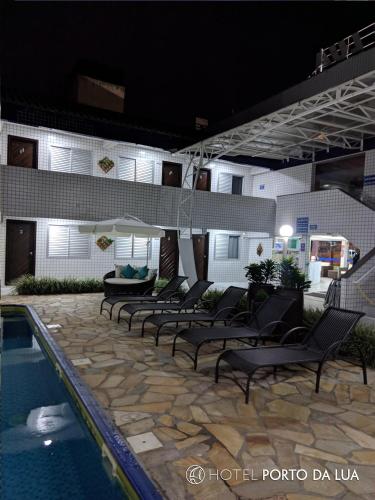 a row of chairs next to a swimming pool at night at Hotel Pousada Porto da Lua in Guaratuba