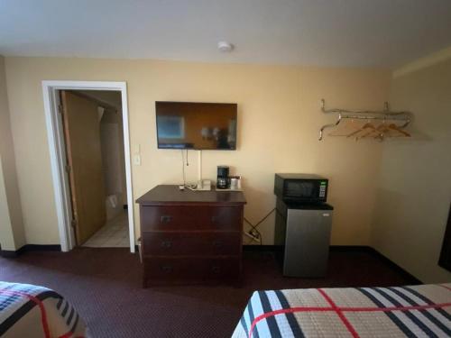 a bedroom with a bed and a dresser and a television at Indian Mound Motel in Fairmont City