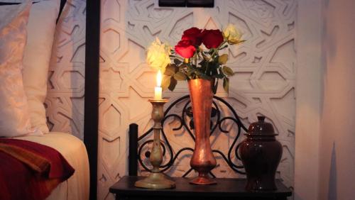 a vase of flowers on a table with a candle at Dar Habache in Marrakesh