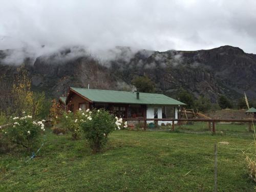 a house in a field with a mountain in the background at Cabañas Emporio de la Meme in San José de Maipo