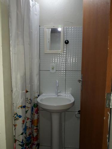 Baño blanco con lavabo y espejo en Casa acolhedora - aluguel por temporada, en Lençóis