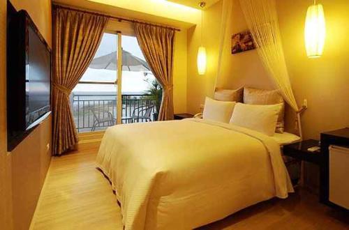 een slaapkamer met een groot wit bed en een televisie bij Golden Bay Holiday Inn in Kenting