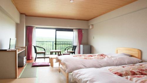 a hotel room with two beds and a balcony at Hotel New Koyo in Kusatsu