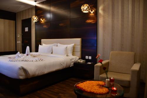 a hotel room with a bed and a chair at Pristine Hotel, Varanasi in Varanasi