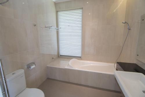 a bathroom with a tub and a toilet and a sink at Sevilla Resort Magelang in Magelang