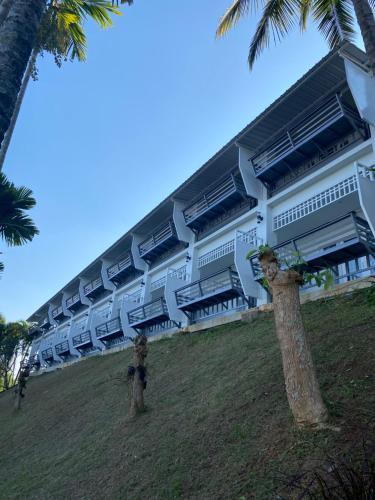 a large white building with palm trees in front of it at โรงแรม ริเวอร์บรีซ เชียงแสน River Breeze Chiangsean in Chiang Saen