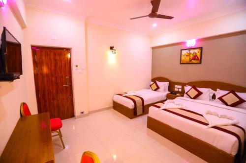 a hotel room with two beds and a television at Nitheesh Residency in Kanchipuram