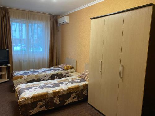 エストサドクにあるКвартира на Эстонскойのベッド2台とキャビネット付きのホテルルームです。