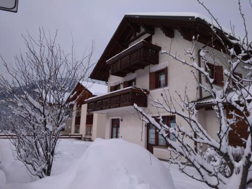 a building covered in snow with trees in front of it at Casa dello Sciatore in Bormio