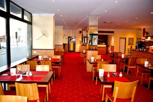 a restaurant with wooden tables and chairs and a red carpet at Hotel Harburger Hof in Hamburg