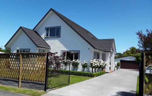 a white house with a black roof and a fence at No. 6 Heathcote in Taupo