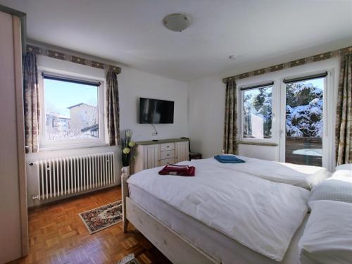 a bedroom with a large bed and two windows at Ferienwohnung Werner in Saalfelden am Steinernen Meer