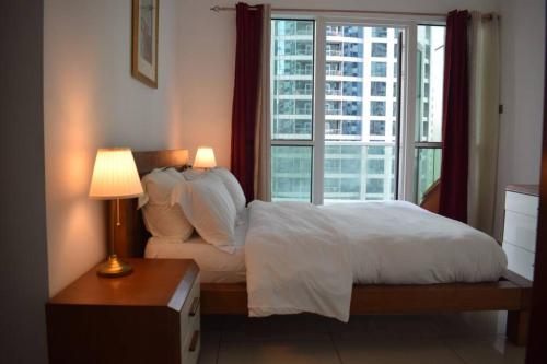 a bedroom with a white bed and a window at skynest holiday homes sea view 1 bedroom apartment dubai marina 1011 in Dubai