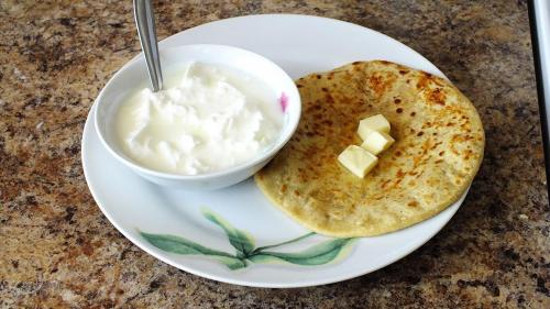a white plate with a bowl of yogurt and a tortilla at Shanti Jungle cottage in Mashobra