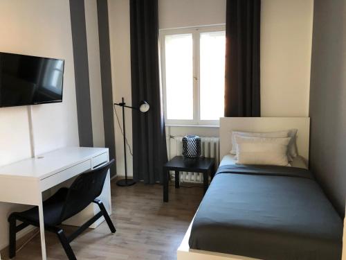 a bedroom with a bed and a desk and a television at Ela Apartments Berlin in Berlin