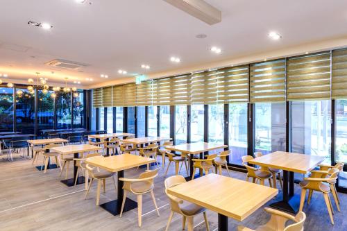 un restaurante con mesas, sillas y ventanas en Shin Shin Hotel Seogwipo en Seogwipo