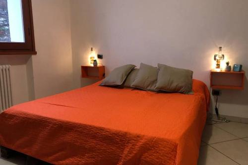 a bedroom with an orange bed with two pillows at Casa nel bosco, Appennino Tosco Emiliano in Camugnano