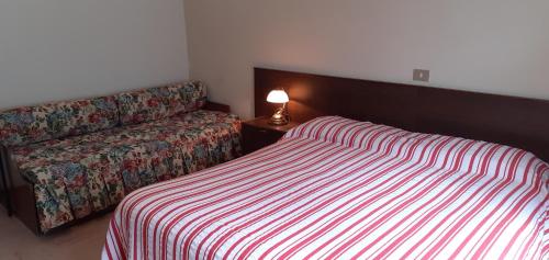 a bedroom with a bed and a chair with a lamp at Hotel Cristallo in Macugnaga