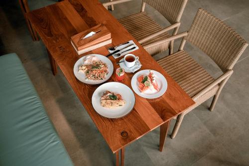 ein Holztisch mit Tellern voller Essen darauf in der Unterkunft One Degree Sunset Hill Leisure in Uluwatu