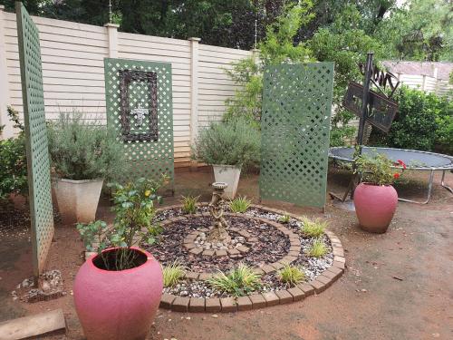 a garden with pink vases and plants in front of a fence at Chic Breeze in Bloemfontein