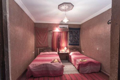 two beds in a hotel room with red sheets at Kasbah Valentine in Aït Ben Haddou