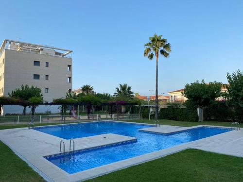 Una piscina con una palmera y un edificio. en Apartamento Aguamar, en Denia