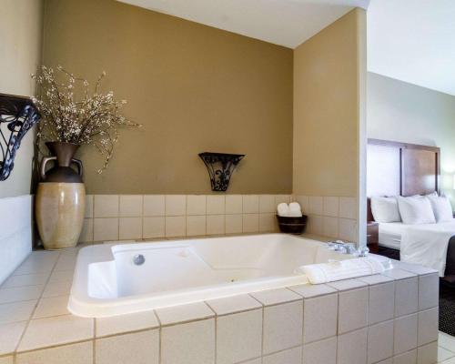 a large white bath tub in a room with a bed at Comfort Inn in Garden City