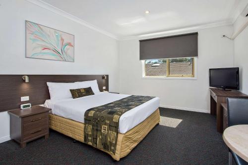 a bedroom with a bed and a flat screen tv at Comfort Hotel Dandenong in Dandenong