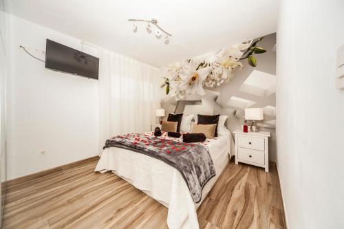 a white bedroom with a bed and a chandelier at Apartamentos los volcanes in Puerto del Carmen