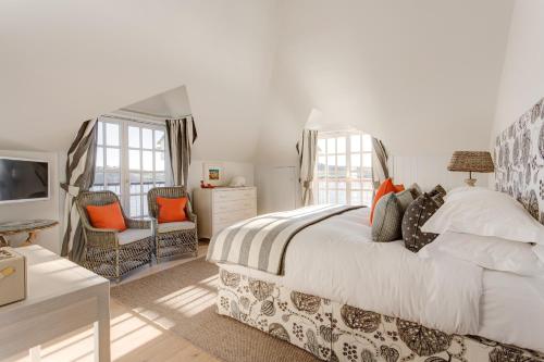 a bedroom with a large bed and two chairs at The Idle Rocks in Saint Mawes