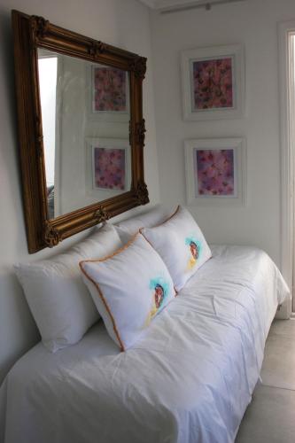 a white bed with pillows and a mirror on the wall at Allegra Dalila Casa Hotel-Arte in Tandil