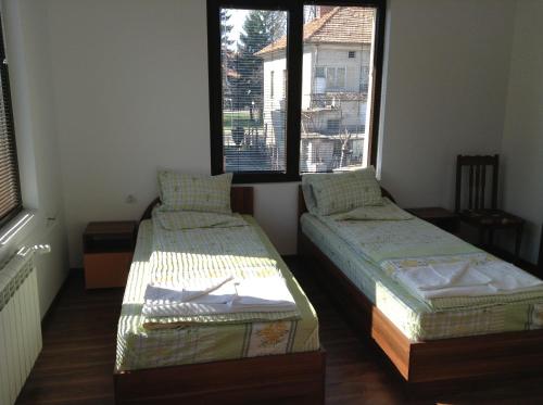 two beds in a room with two windows at Guest House Luchi in Varshets