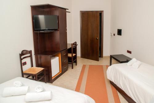 a hotel room with two beds and a television at Hotel George in Korçë