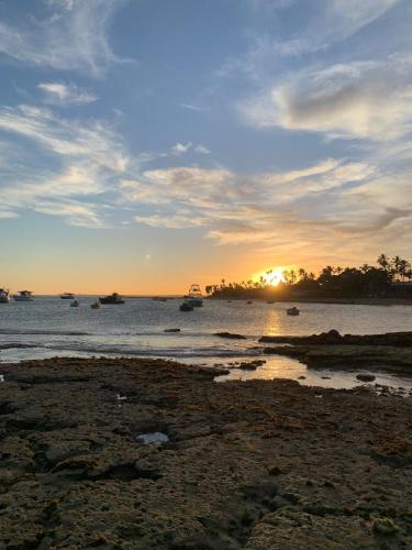 a sunset on a beach with boats in the water at Pousada Du’Forte in Praia do Forte
