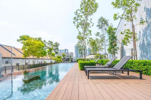 a swimming pool with two lounge chairs next to a building at 9am-5pm, SAME DAY CHECK IN AND CHECK OUT, Work from Home, Comfy & Quiet Tamarind Suites-Cyberjaya by Flexihome-MY, in Cyberjaya