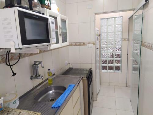 Guarujá Enseada - Apto 200m da praia - 02 dorm. Wi-fi + AR + Estacionamento في غوارويا: مطبخ صغير مع حوض وميكروويف