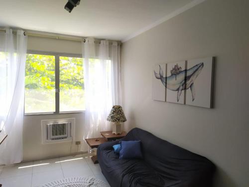 Guarujá Enseada - Apto 200m da praia - 02 dorm. Wi-fi + AR + Estacionamento في غوارويا: غرفة معيشة مع أريكة ونافذة